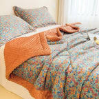 Floral bedding set with orange throw on a bed