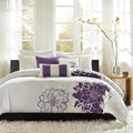 Bedroom with white bedding and purple floral patterns, featuring a bed and side table.
