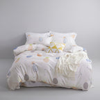 Bed with patterned bedding in a room with a lamp, plant, and decorative items.