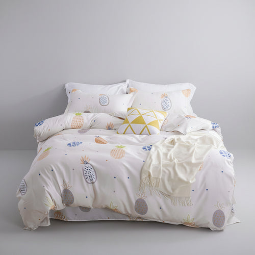 Bed with patterned bedding in a room with a lamp, plant, and decorative items.