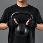 Person holding a black kettlebell with gloves on a gray background