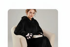 A woman seated in a cream armchair wearing a black hooded robe with oversized paw-print glove details on the sleeves and lap. The image includes marketing text at the top reading 'Appealing Creature Aesthetic For Home' and '200-250Gsm With Snapconversion Design'.