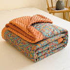 Folded floral quilt with orange minky fabric on a bed